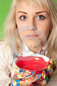 Attractive girl with colorful hands a cup of red paint