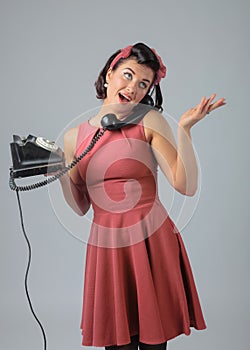 Attractive girl in a coral dress emotionally talking on the phone