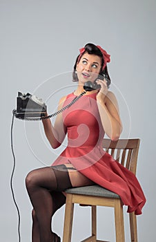 Attractive girl in a coral dress emotionally talking on the phone