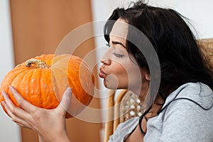 Attractive girl with dark hair kissing pumpkins