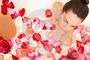 Attractive girl enjoys a bath with milk and roses