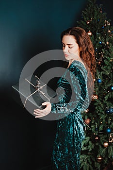 Attractive girl with gift box near Christmas tree