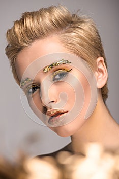 attractive girl with golden glitter on face looking at camera