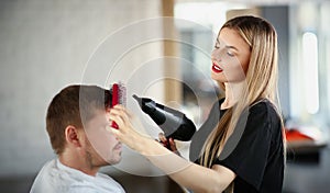 Attractive girl hairdresser doing hair styling to a man
