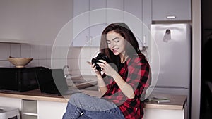 Attractive girl in her 20`s is smiling while looking through the photos on her camera.