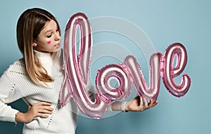Attractive girl hold love pink balloon on valentine day. Beautiful blonde young teen model laugh smiling wide. Love word balloons
