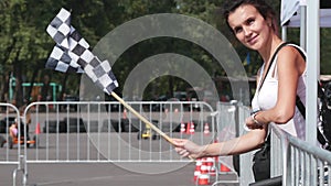 Attractive girl holding and waving checkered race flag on a kart race. The brunette announces the final lap of the race