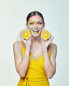 Attractive girl holds orange slices in front of her face