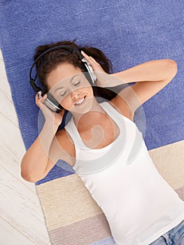 Attractive girl laying on floor enjoying music