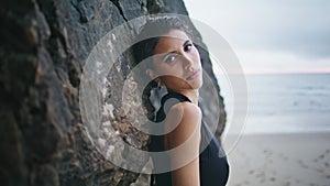 Attractive girl leaning beach cliffs closeup. Sexy model posing sandy seashore