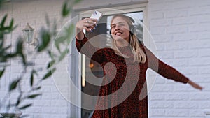 Attractive girl listening to music and dancing with smartphone in hands on balcony of house rbbro.