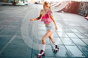 Attractive girl is looking down to the right and rollerblading. She is professional. Girl is doing different moves and