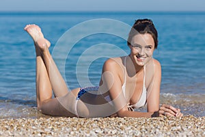 Attractive girl lying on pebble at waters edge