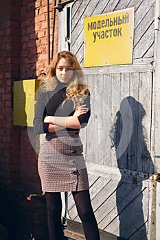Attractive girl near factory door with warning plates