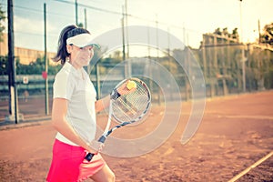 Attractive girl playing tennis and smiling at camera. Healthy modern lifestyle with sportswoman and accesssories