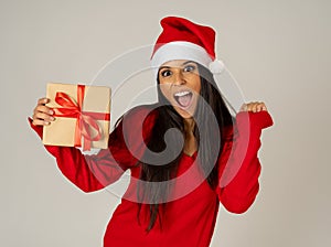 Attractive girl posing in red dress and santa hat isolated on grey background