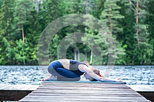 Attractive girl practicing yoga, sitting in Child exercise, Balasana pose  on the lake. The concept of appeasement,  healthy