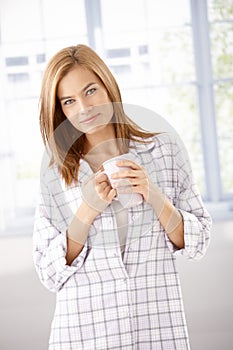 Attractive girl in pyjama drinking tea smiling