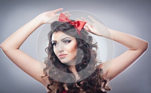 Attractive girl with a red bow on her head and red bra send a kiss. Pinup model on grey background. Beautiful pinup model