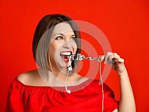 Attractive girl in red dress holding a fork in hands. on the headphone plug. prepared to eat.