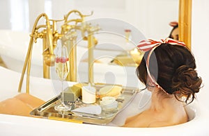 Attractive girl relaxing in bath on light background