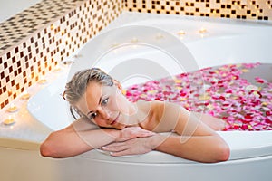 An Attractive girl relaxing in bath with rose petals