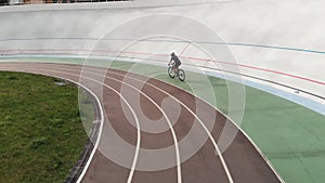 Attractive girl on road bike is riding on bicycle path at velodrome. Young sportive woman training at cycling track