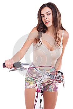 Attractive girl, sitting on a bicycle and smiling. Isolated on white background.