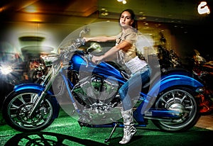 Attractive girl sitting on a blue motorcycle, moto show