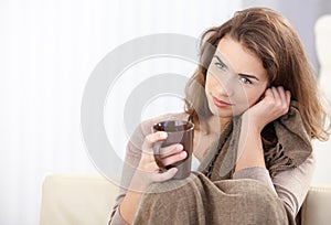 Attractive girl sitting on sofa drinking tea