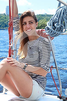 Attractive girl is sitting on a yacht at summer day