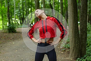 Attractive girl in sportswear is doing gymnastic exercises on the track in the forest park
