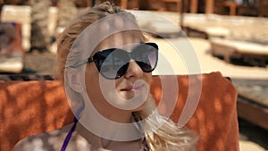 Attractive girl in sunglasses looks at the sea on public beach in Egypt.