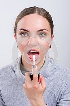 Attractive girl taking a medicine with spray inside the throat on light background