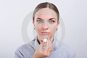 Attractive girl taking a pill on light background