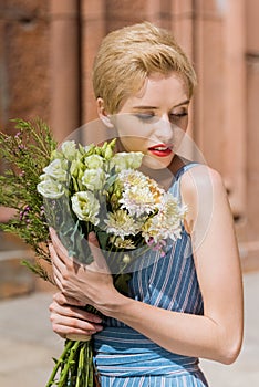 attractive girl in trendy dress holding bouquet