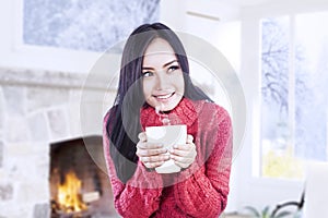 Attractive girl warming at fireplace hold coffee