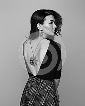 Attractive girl wearing backless dress and spider necklace. Black and white.