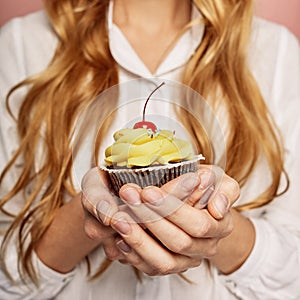 Attractive girl in a white shirt is holding cupcakes