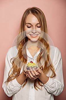 Attractive girl in a white shirt is holding cupcakes