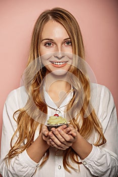 Attractive girl in a white shirt is holding cupcakes