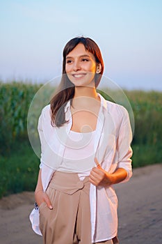 Attractive girl in white shirt posing on country road in sunset