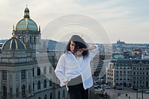 Attractive girl in white t-shirt and cardigan stands on the roof.