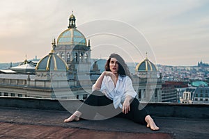 Attractive girl in white t-shirt and cardigan stands on the roof.