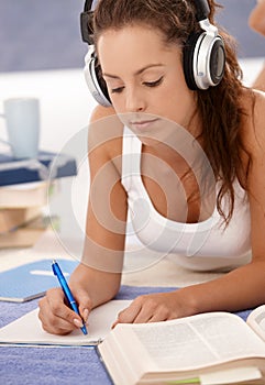 Attractive girl writing homework laying on floor