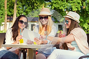 Attractive girlfriends enjoying cocktails and using wireless connection on digital tablet