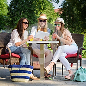 Attractive girlfriends enjoying cocktails and using wireless connection on digital tablet