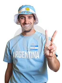 Attractive guy with argentinian jersey and hat showing victory sign