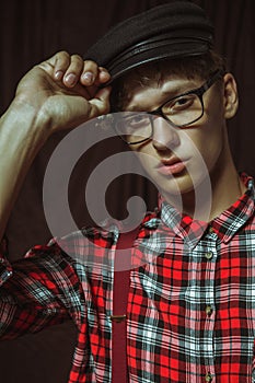 Attractive guy in glasses corrects his cap