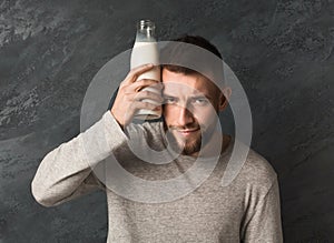 Attractive guy with headache holding milk bottle photo